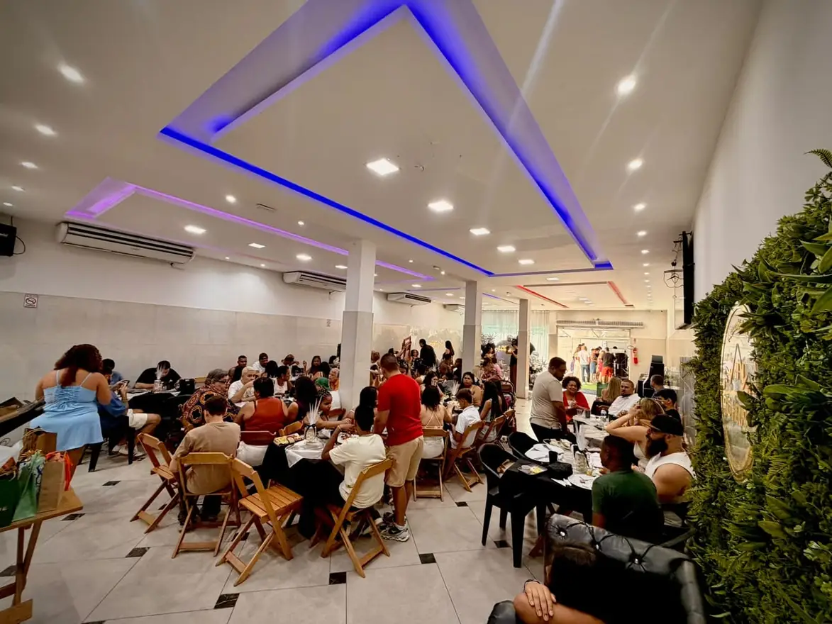 Festa lotada no salão do Espaço Big House com convidados às mesas e iluminação azul